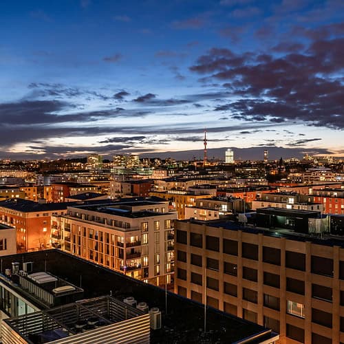 Beleuchtete Häuser in München bei Abenddämmerung als Motiv für IT, Software und KI