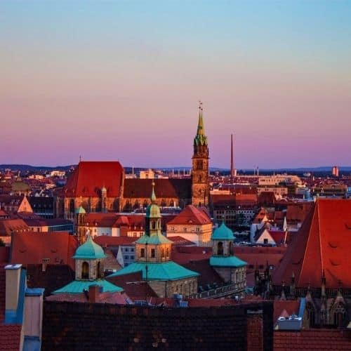 Blick über die historische Nürnberger Altstadt mit Kirchtürmen und roten Dächern bei Sonnenuntergang