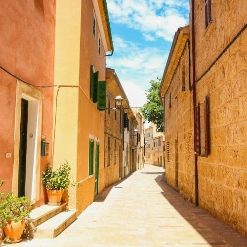 Sonnige Altstadtgasse mit Natursteinhäusern auf Mallorca